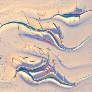 Soft currents of light and color flow across a pale, textured surface, where sinuous blue-green lines trace an abstract landscape shaped by motion, pressure, and time.